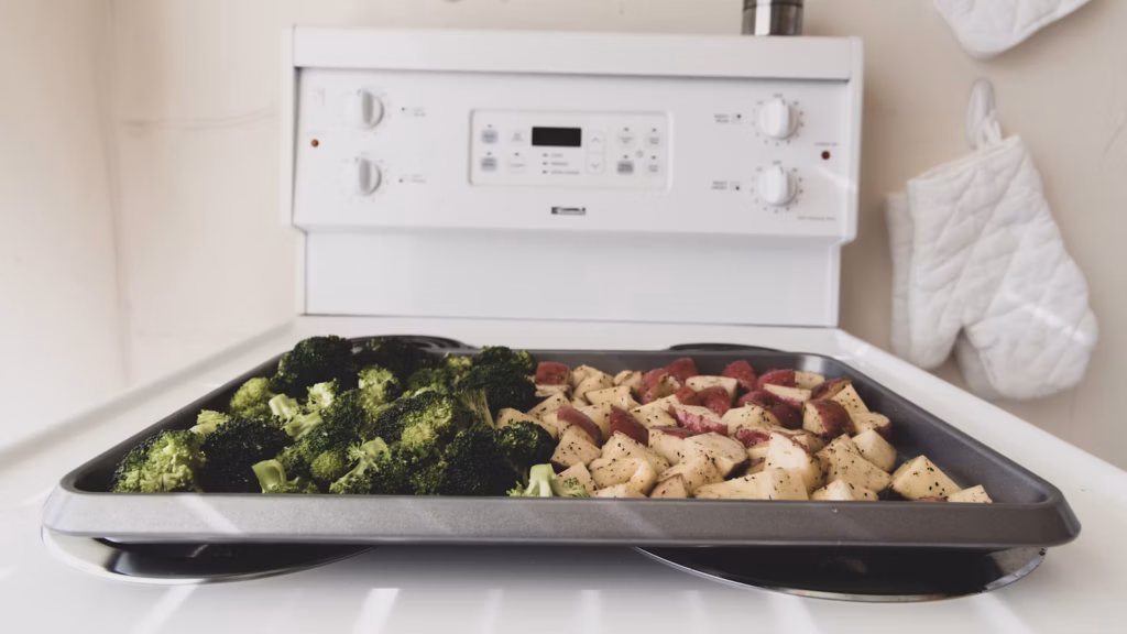 Seasoned broccoli and potatoes arranged for roasting