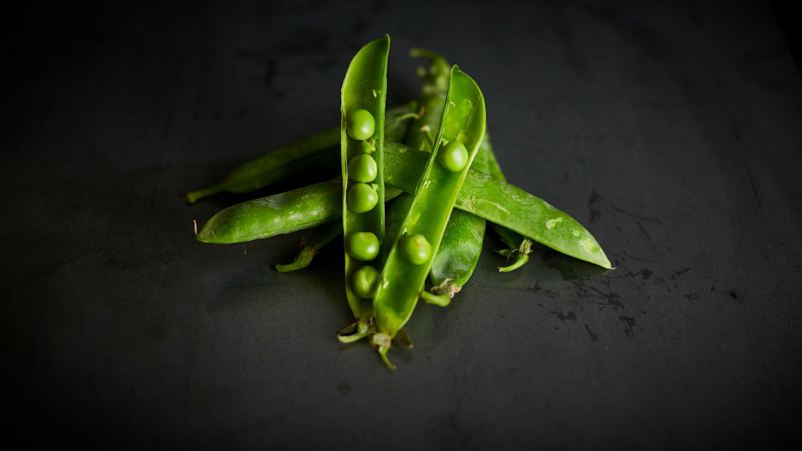 Round garden peas inside opened pods for comparison with snow peas