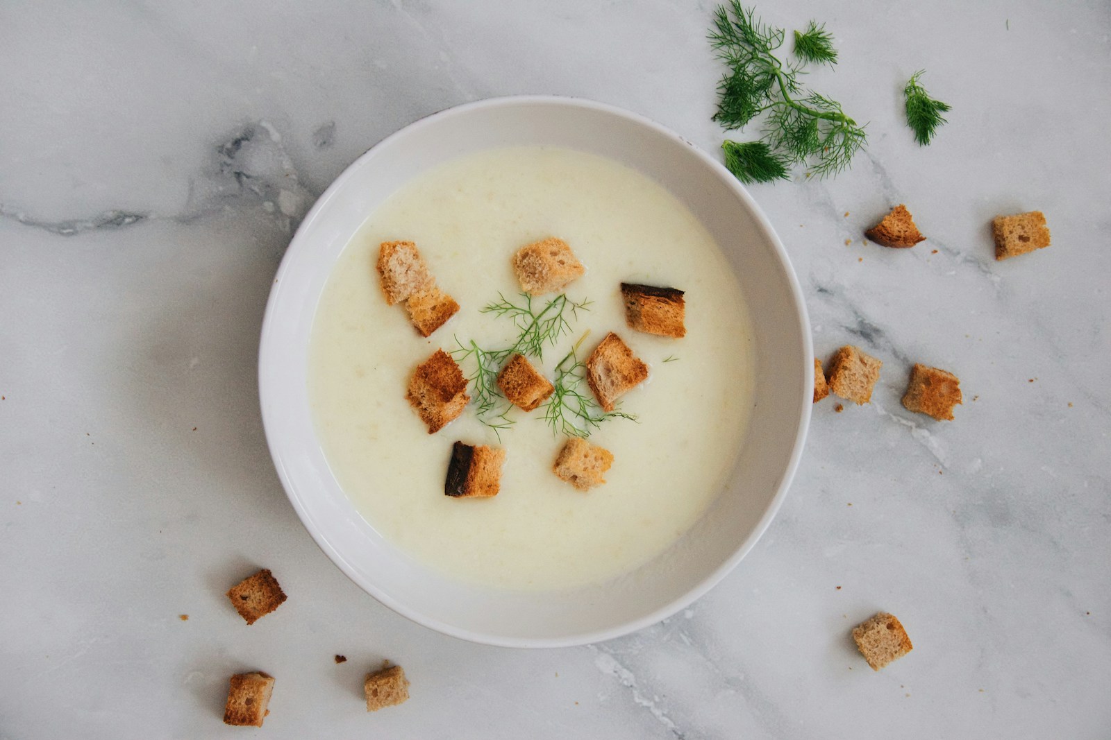 Creamy pale soup with croutons and fresh dill
