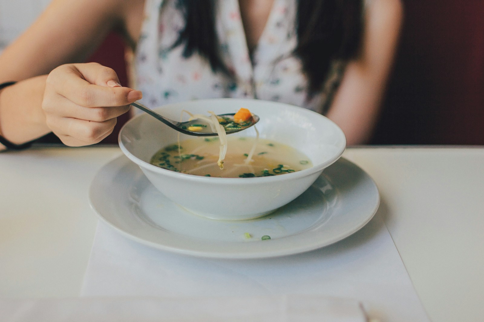 Person lifting a spoonful of vegetable soup