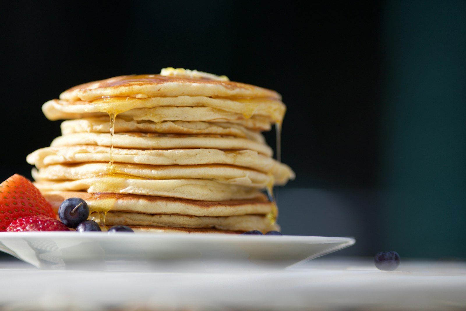 A stack of pancakes with syrup and berries