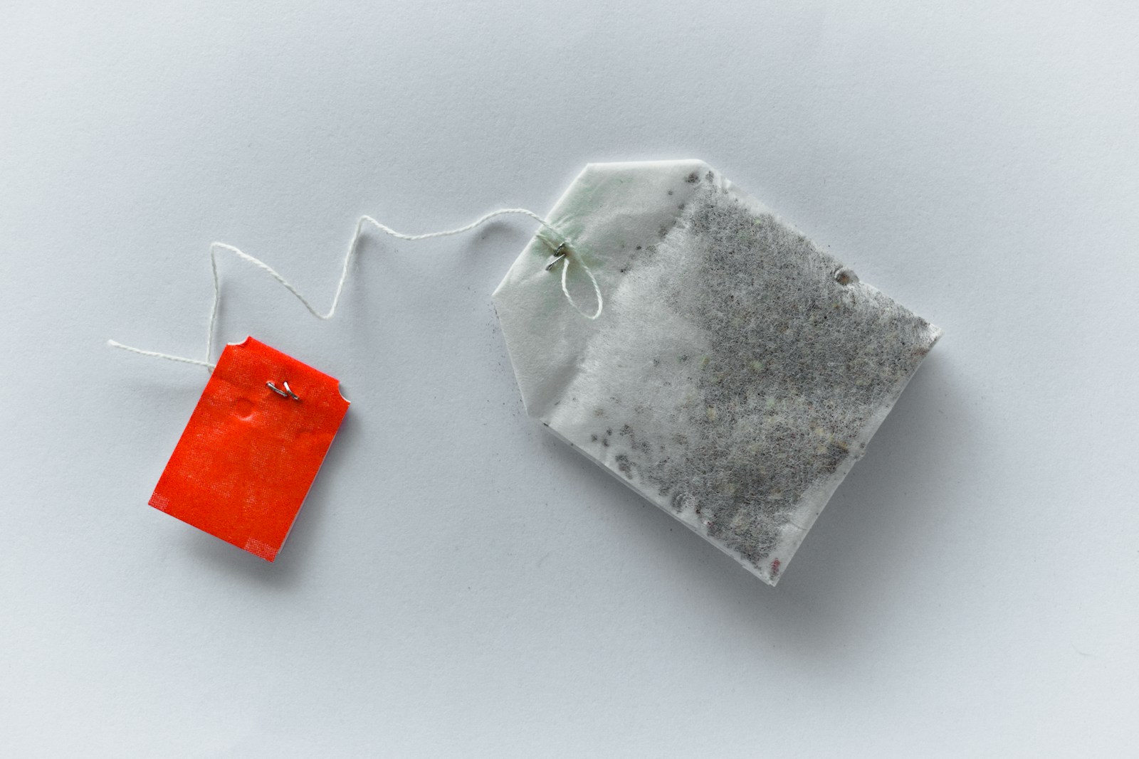 Paper tea bag with a red tag on a pale tabletop