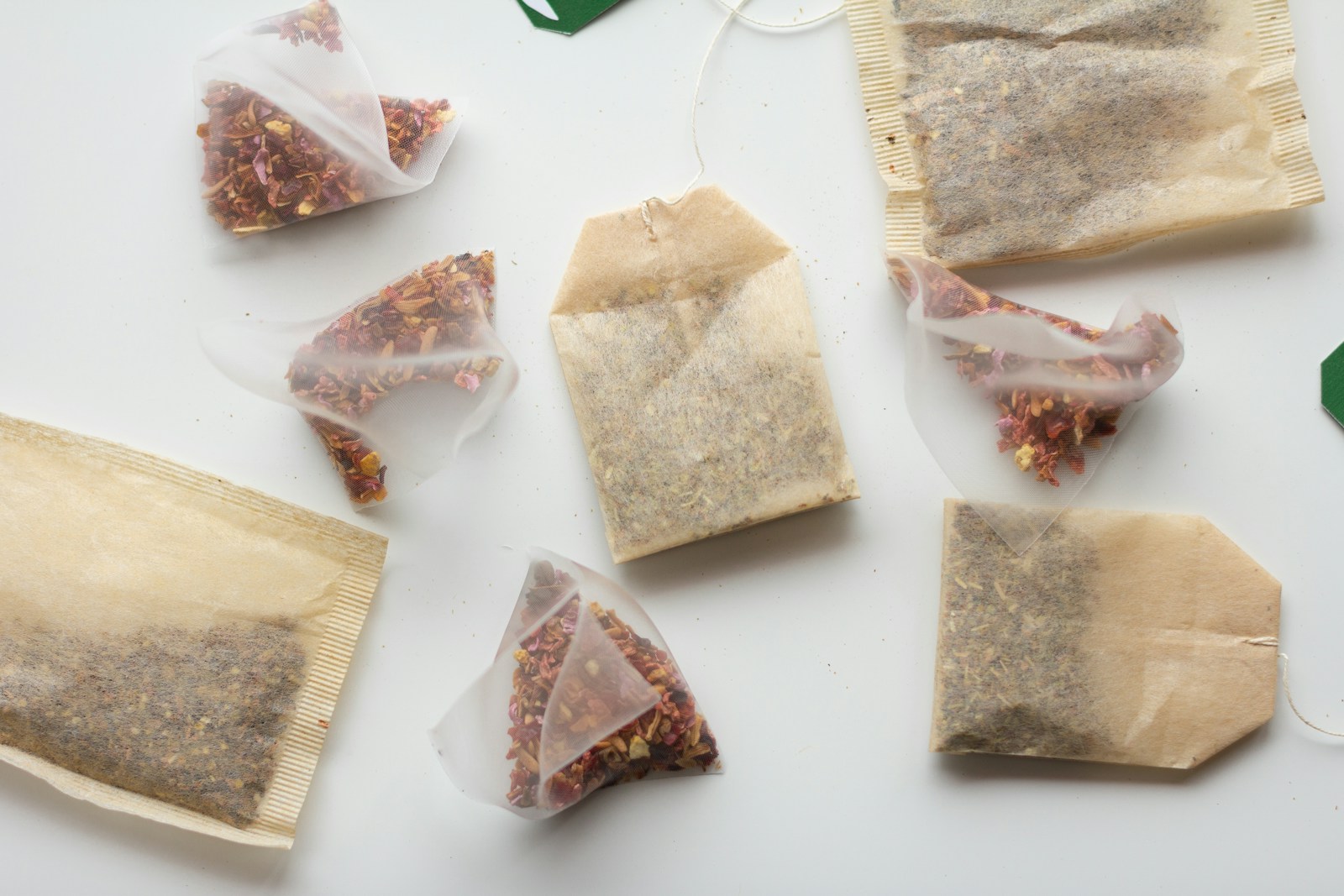 Several paper tea bags and pyramid sachets on a light surface