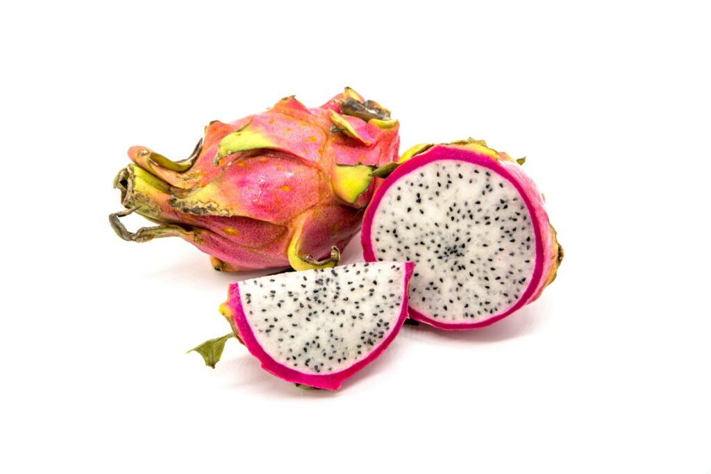 Whole dragon fruit and a cut half showing white flesh and black seeds