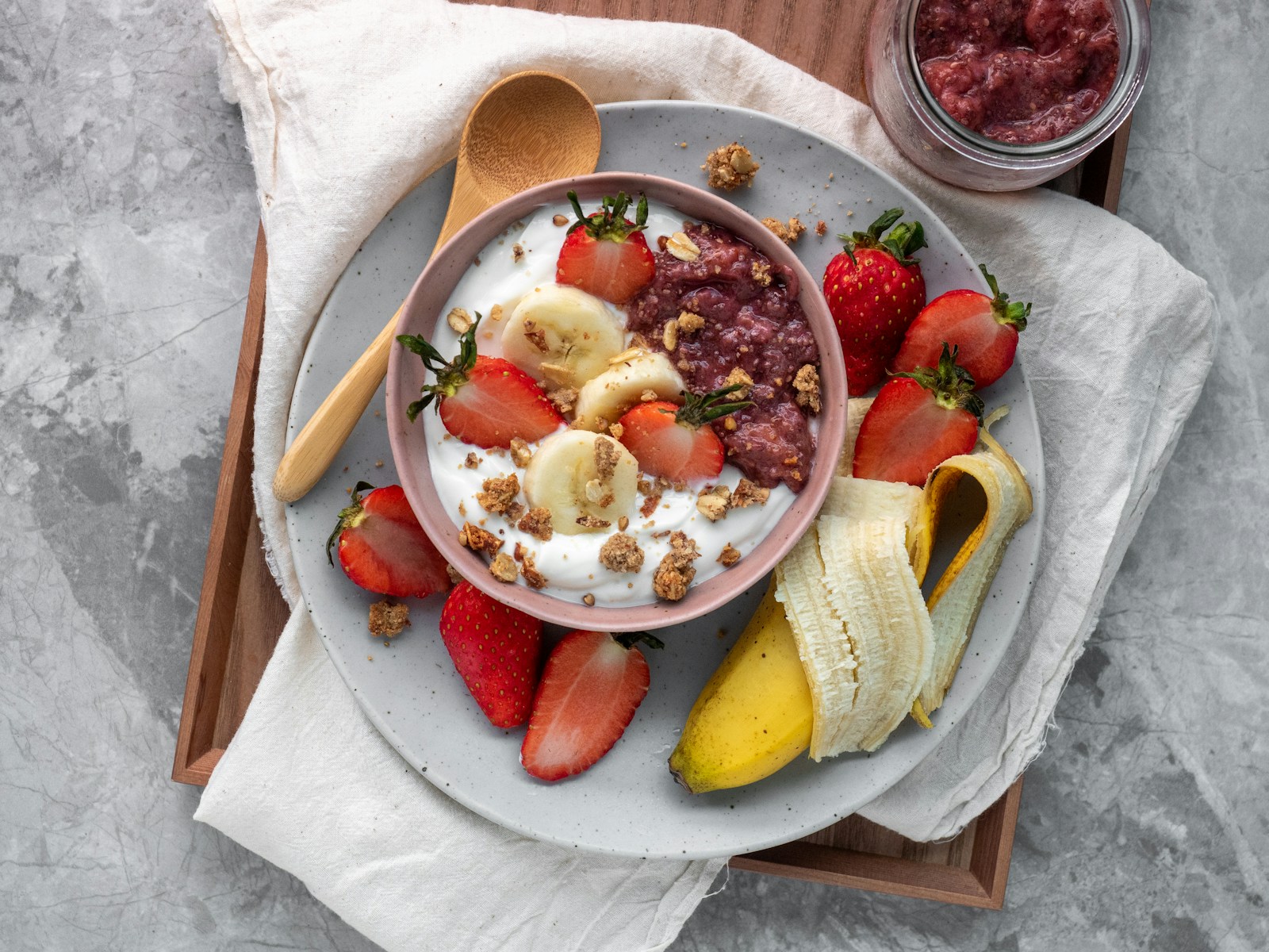 Yogurt topped with strawberries, sliced banana, and granola